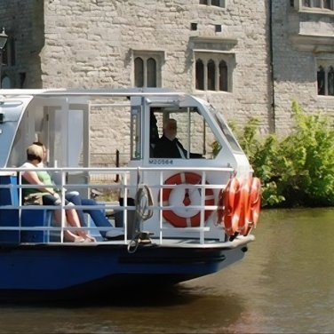 Kentish Lady barge boat on the scenic River Medway passing a historic looking buiding